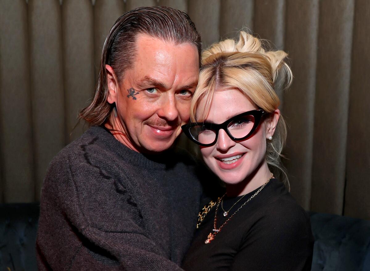 Sid Wilson and Kelly Osbourne smile at the camera and hug.
