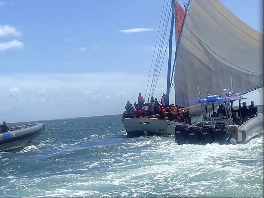 In this image posted on the USCGSoutheast Twitter page, rescue crews safely transfer people from a grounded vessel believed to be carrying migrants, to U.S. Coast Guard ships, Saturday, Aug. 6, 2022, off the coast of Key Largo, Fla., near the gated community of Ocean Reef. (Courtesy of U.S. Coast Guard via AP)