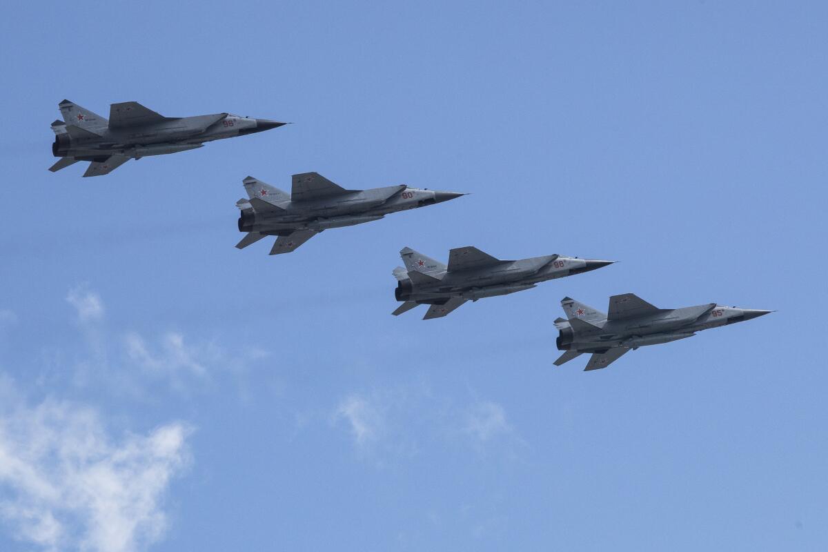 Four military jets fly across a blue sky