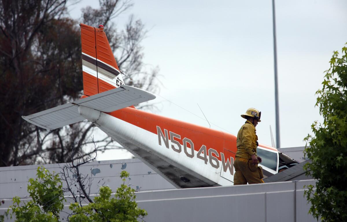 On Sunday, a firefighter surveys the scene where a single-engine plane crash-landed on a building in Pomona.