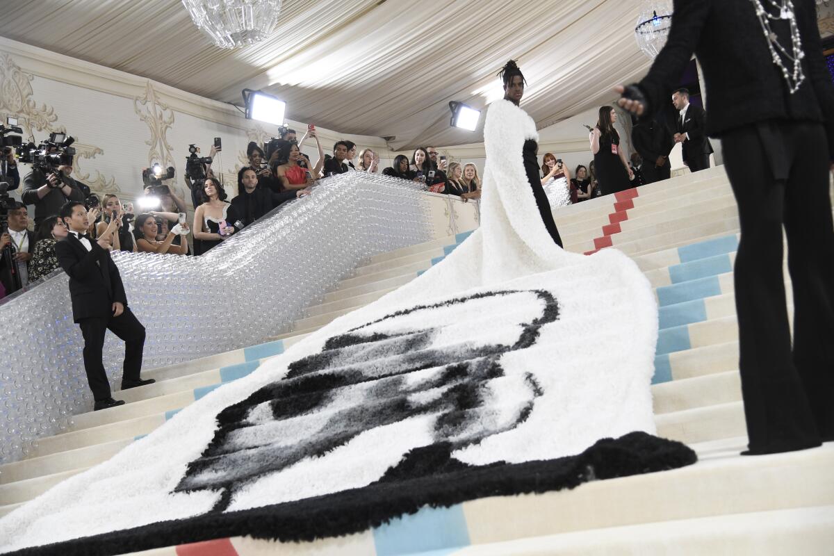 The train of Jeremy Pope's cape with an image of Karl Lagerfeld extends down steps 
