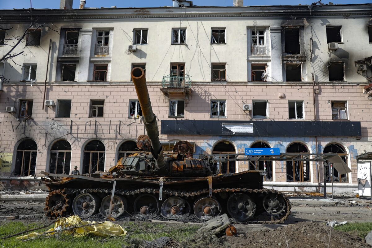 A tank sits in front of a building with blown-out windows 