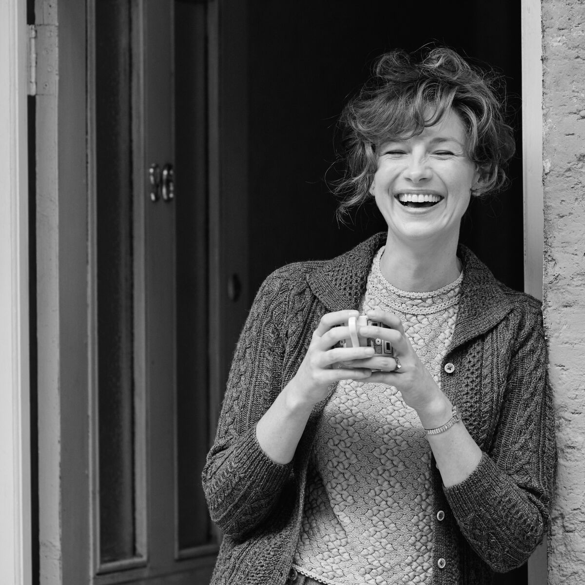 Caitriona Balfe laughs in a doorway as Ma in the black and white "Belfast." 