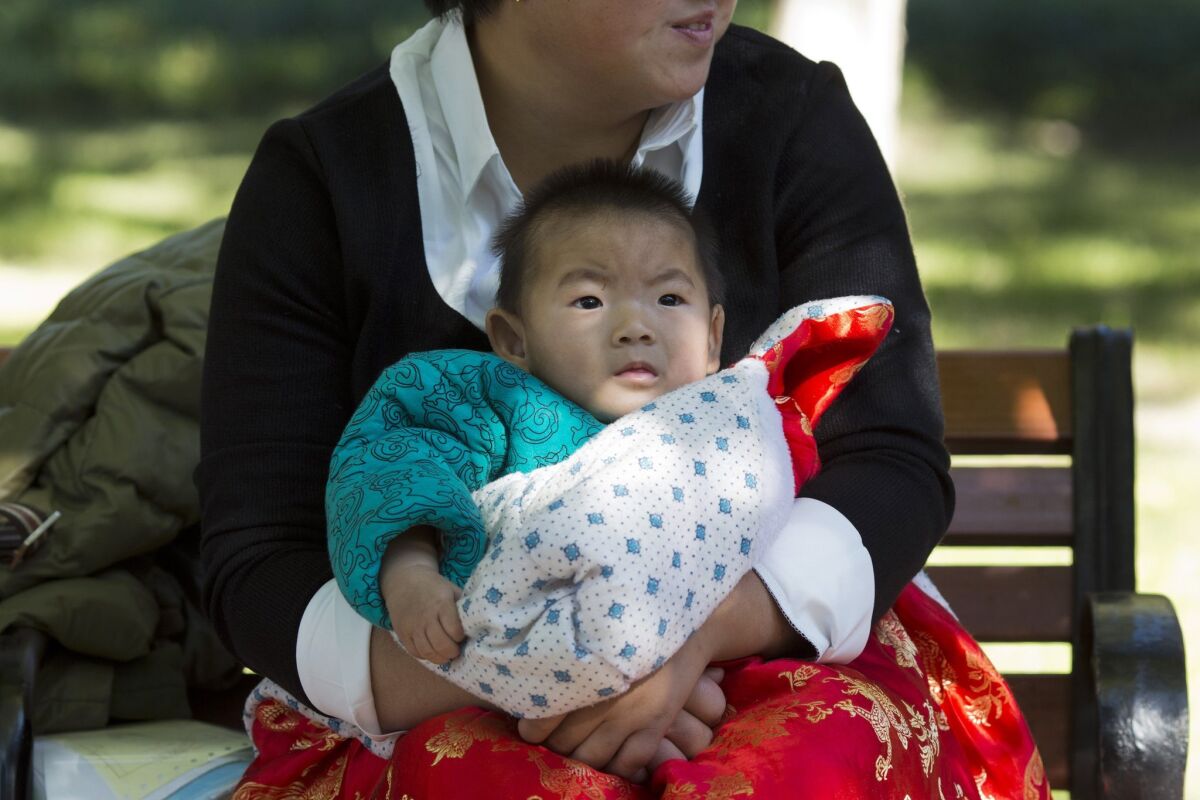 A child is wrapped up against the cold at a Beijing park on Oct. 30, the day after China loosened its one-child policy.