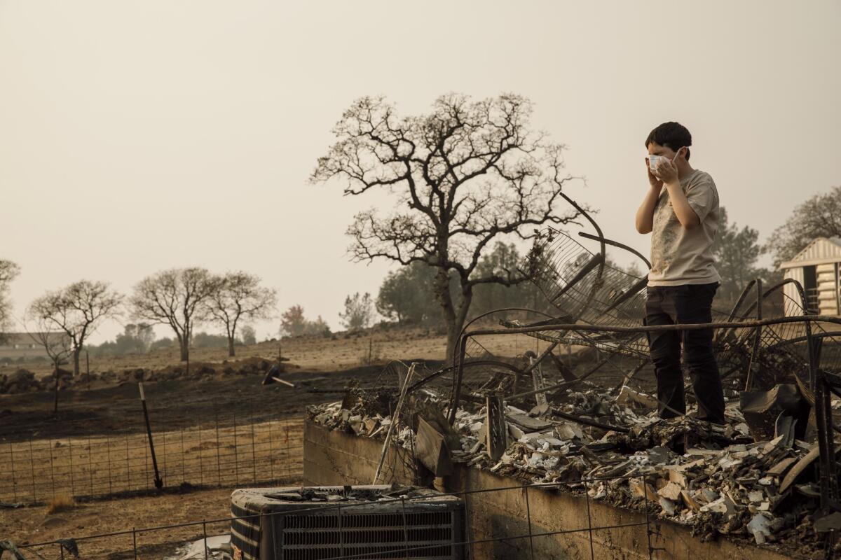 Jeremy Saylors wears a breathing mask as his family returns on Nov. 18, 2018, to the ruins of their home in Paradise, Calif., which was destroyed by the Camp fire.