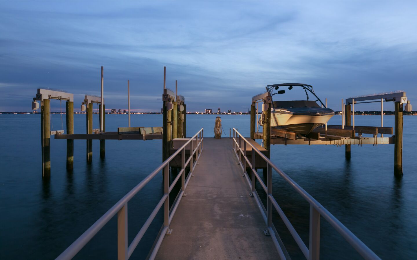 A boat occupies the dock; in the distance are city lights.
