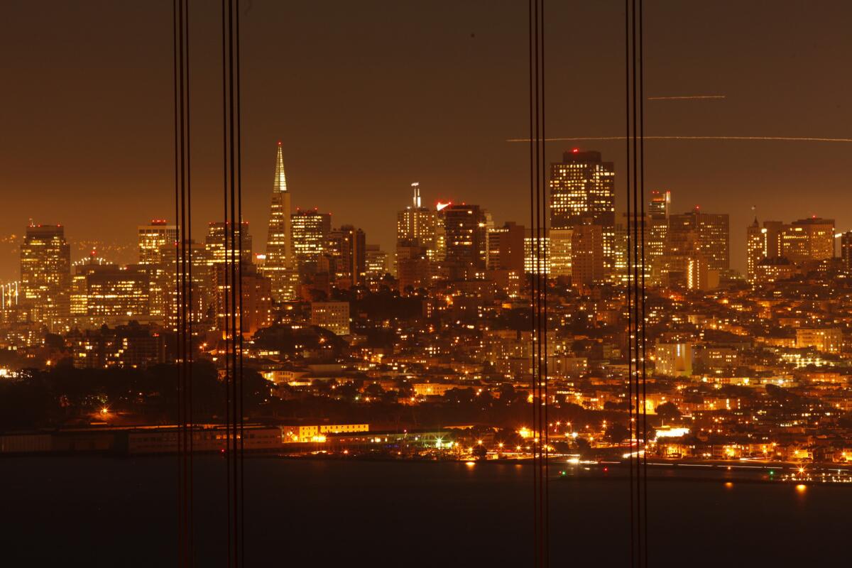 Framed by wires from the Golden Gate Bridge, the San Francisco skyline shimmers in the evening just after sunset. San Francisco is the most expensive destination for business travelers, a new study shows.