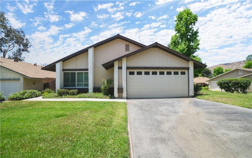 House with large garage door. If front are grass at left with driveway at right