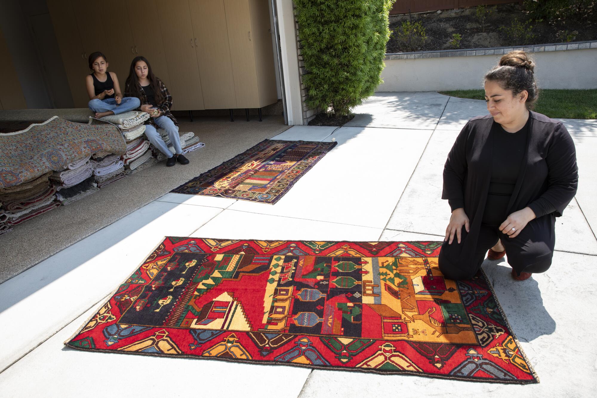 Nargis Habib, 33, looks at a vintage Baluch rug