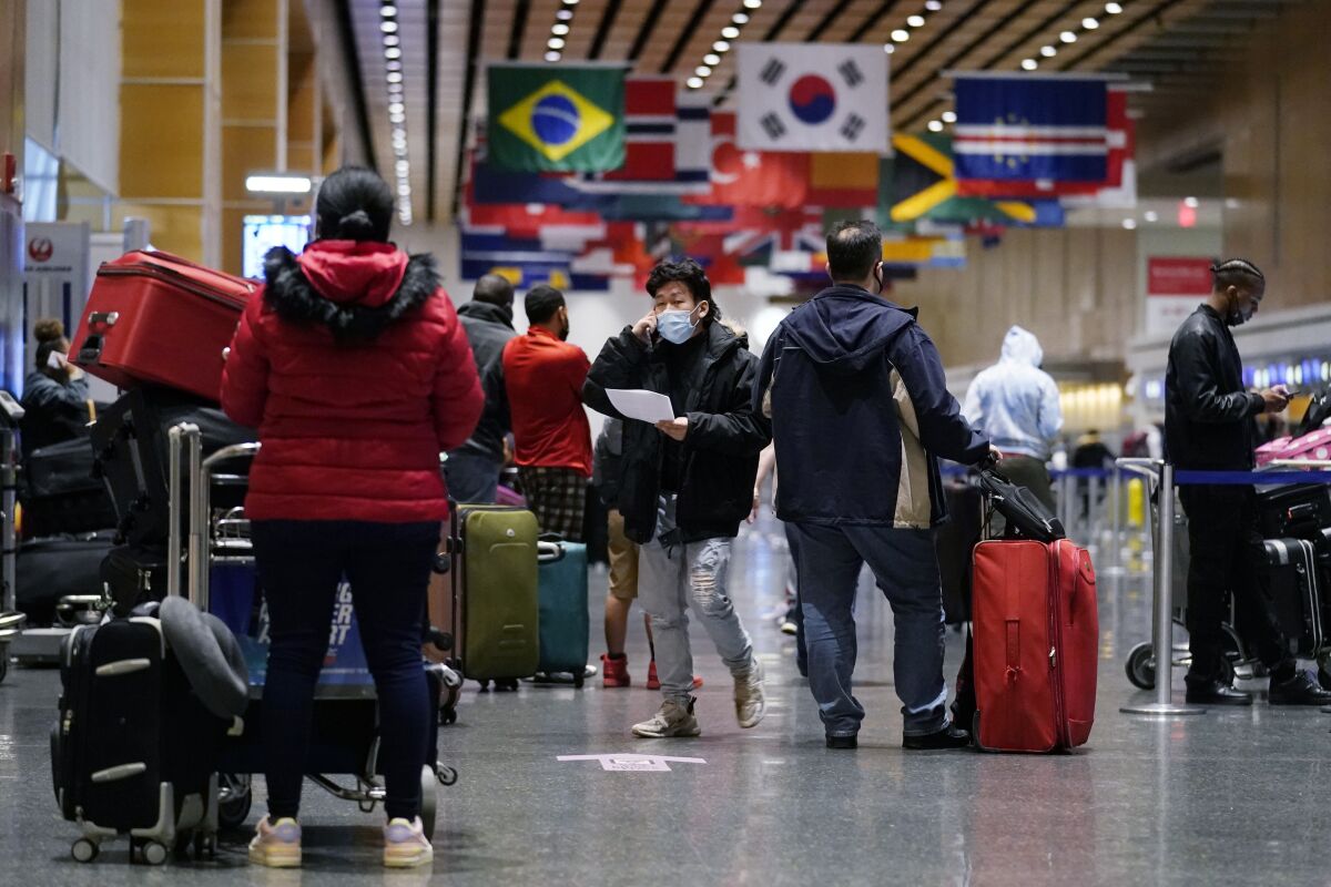 Travelers, surrounded by luggage, wait in line.