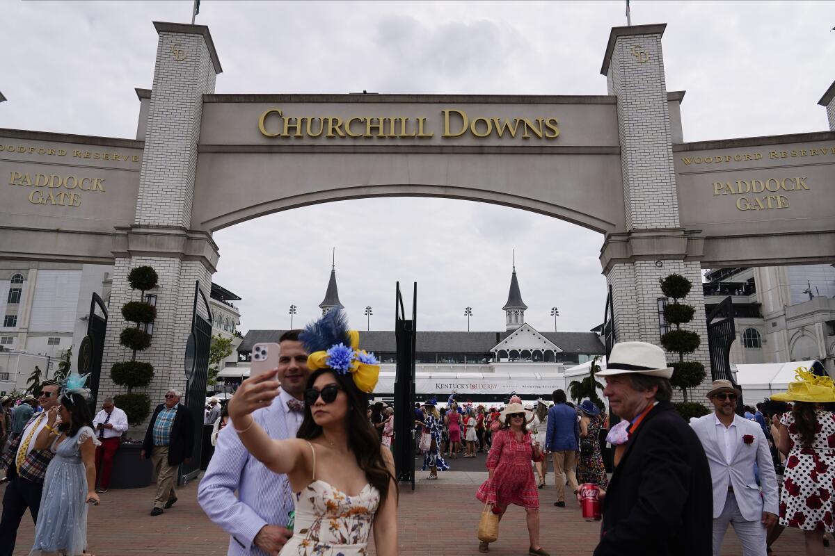 People walk on the grounds of Churchill Downs before the 149th running of the Kentucky Derby 