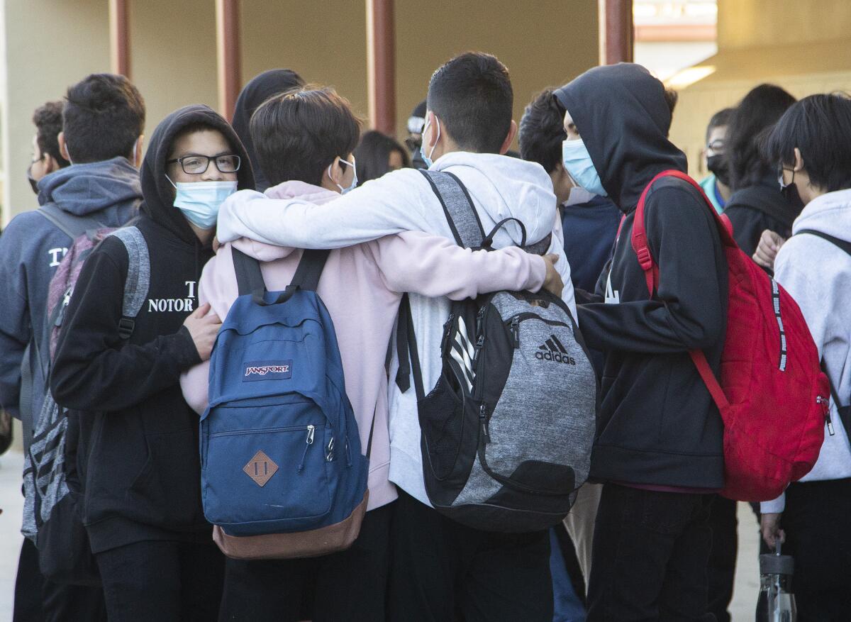 Young people in masks and backpacks stand in a group. 