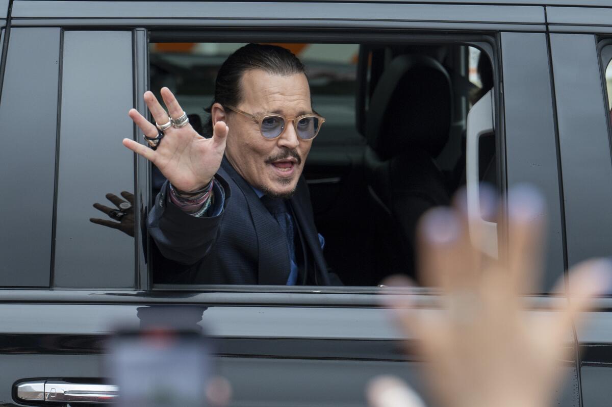 Johnny Depp waves out the window of a black SUV outside the courthouse during his defamation trial