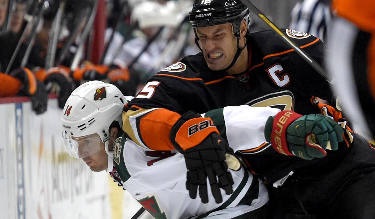 Ducks center Ryan Getzlaf puts Wild right wing Justin Fontaine into the boards during the first period of their game Friday night at Honda Center.