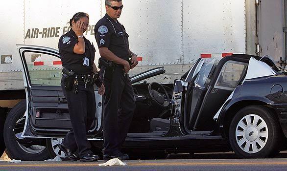 LAPD investigators survey the scene of a crash between a police cruiser and a big rig at 35th and Western streets. An LAPD cruiser rear-ended the truck and slid partway under the trailer.