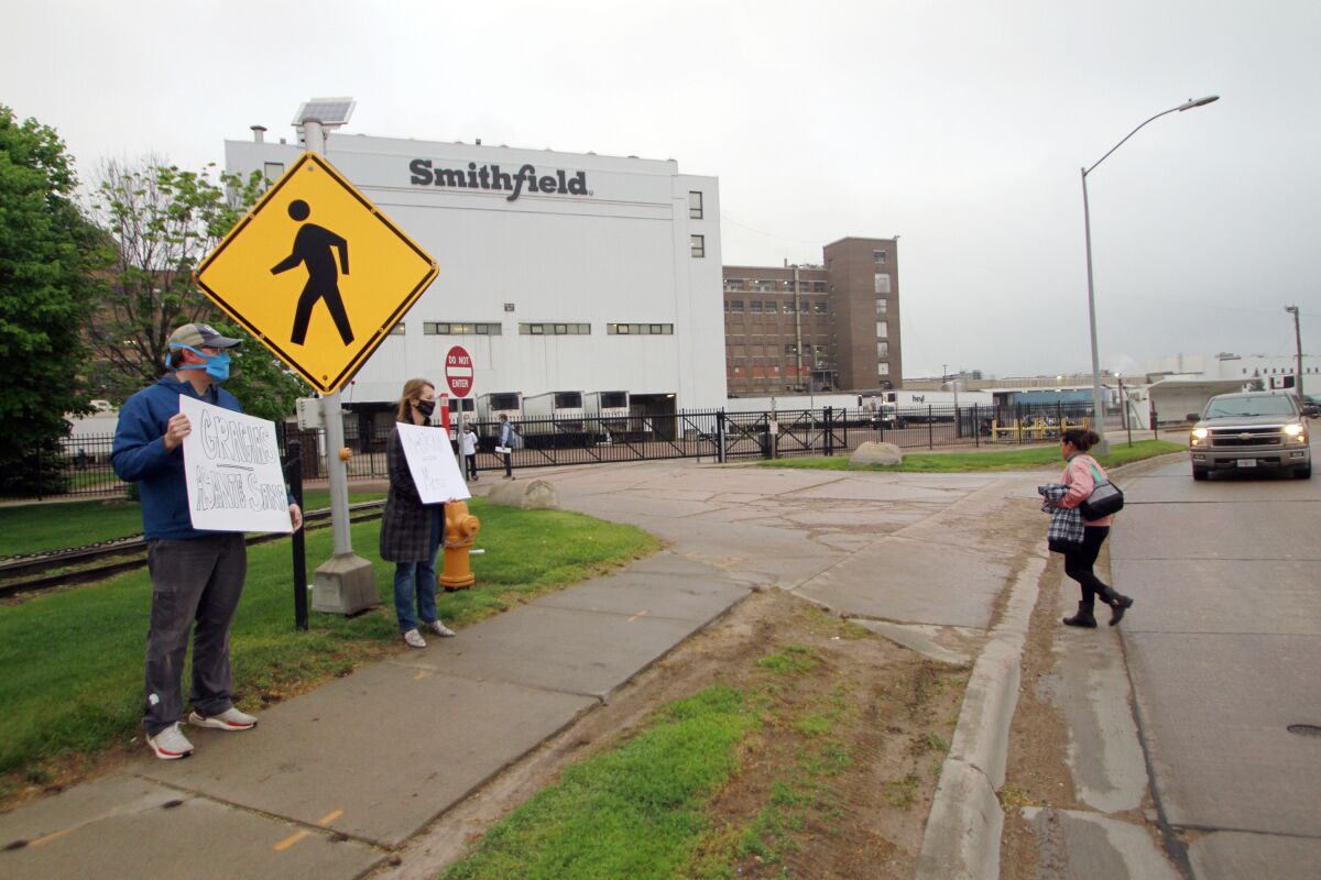 FILE - In this May 20, 2020, file photo, residents cheer and hold thank you signs to greet employees of a Smithfield pork processing plant as they begin their shift in Sioux Falls, S.D. Federal regulators said Thursday, Sept. 10, 2020, they have cited Smithfield Foods for failing to protect employees from exposure to the coronavirus at the company's Sioux Falls plant, an early hot spot for virus infections that hobbled American meatpacking plants. (AP Photo/Stephen Groves, File)