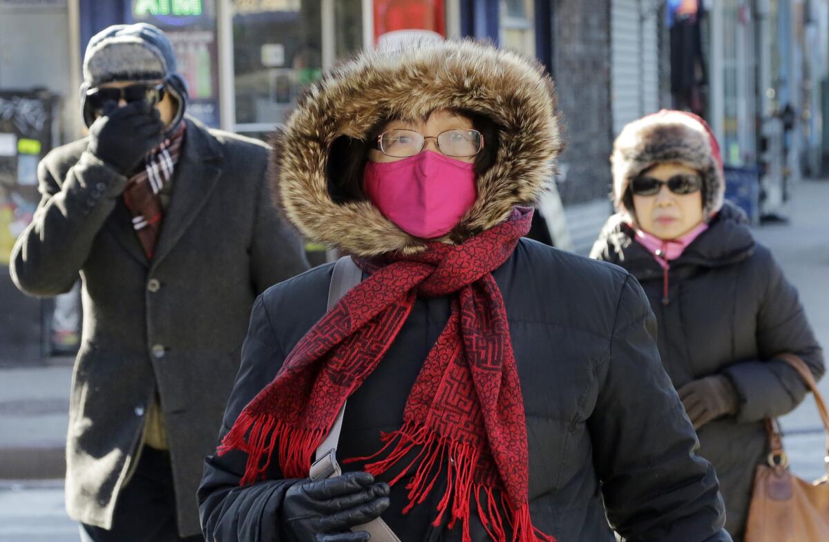 People are bundled up as they walk in cold weather in Queens, N.Y.