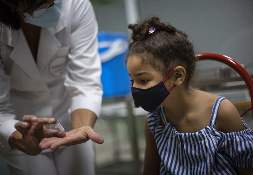 Una enfermera muestra un frasco de la vacuna Soberana-02 de fabricación cubana contra el COVID-19 antes de administrarle una dosis a una niña en La Habana, Cuba, el martes 24 de agosto de 2021. (AP Foto/Ramon Espinosa)