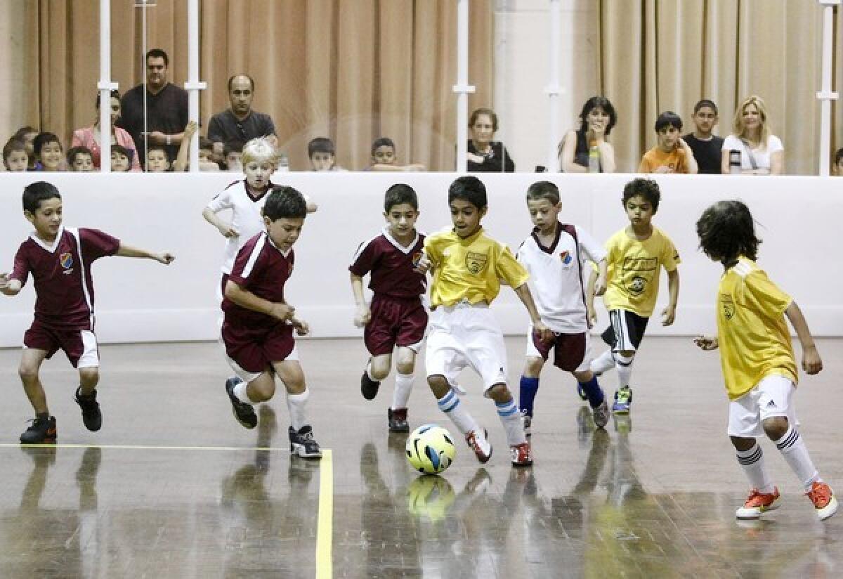 With parents and other players watching, children enjoy the first-ever indoor soccer match during the grand opening of the Indoor Soccer Rink at Glendale Civic Auditorium on Saturday, June 8, 2013. The rink is removable and can be put up and taken down as needed.