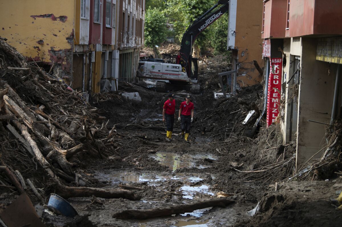 Rescue workers walk in a street in Bozkurt town of Kastamonu province, Turkey, Sunday, Aug. 15, 2021, after flooding. Turkey sent ships to help evacuate people and vehicles from a northern town on the Black Sea that was hard hit by flooding, as the death toll in the disaster rose Sunday to at least 62 and more people than that remained missing. (AP Photo)