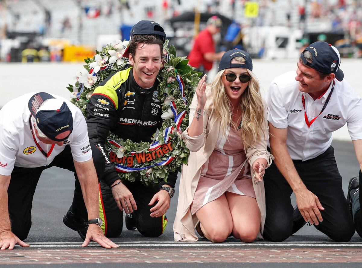 Simon Pagenaud, second from left, and his fiancee, Hailey McDermott, laugh after kissing the bricks at the finish line following Pagenaud's win in the Indianapolis 500.