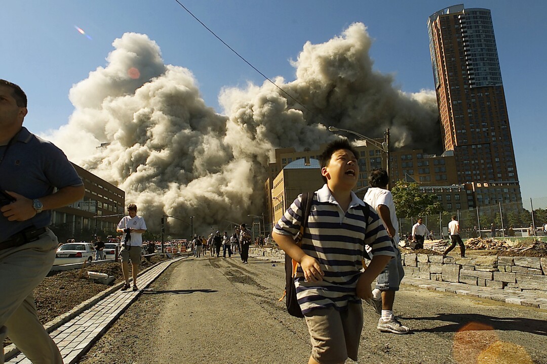 People run away as smoke fills a street behind them