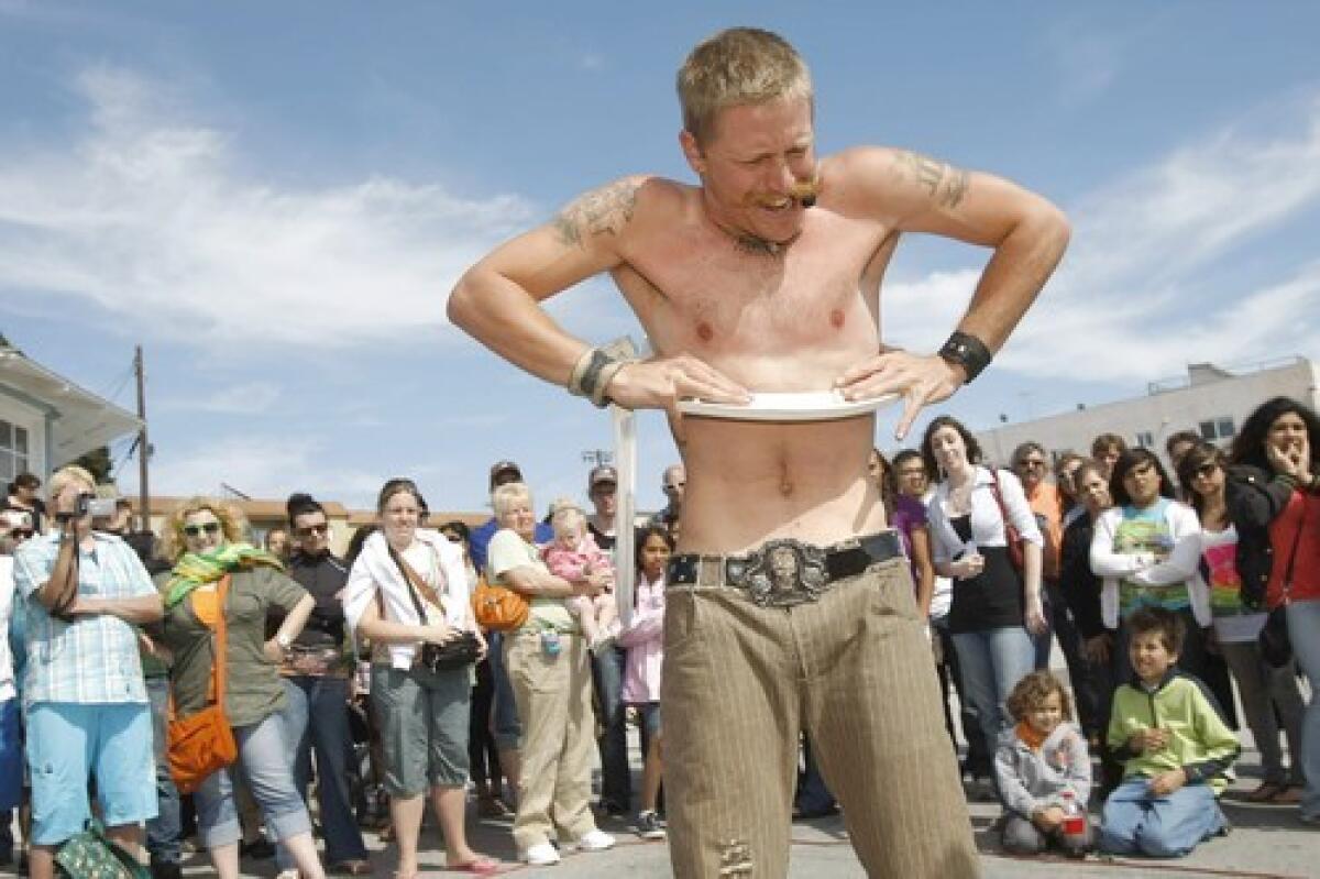 A TIGHT SQUEEZE: Contortionist Mason Davis, who performs as Masonious Max, fits his body through a toilet seat on Venice Boardwalk.