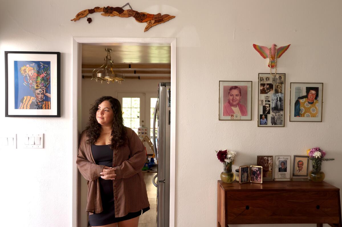 A woman leans against doorway in a home.