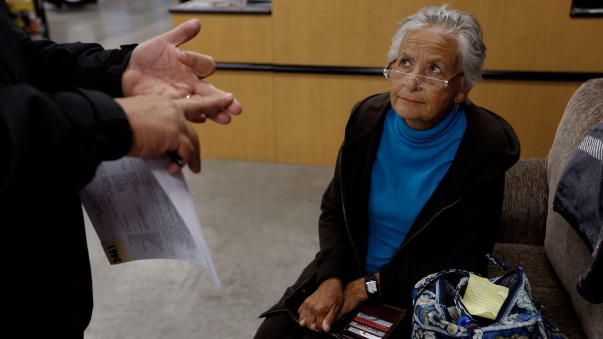 Dolores Westfall, 79, who lived in an RV for seven years while following work around the country, listens to the estimate on needed repairs for her RV, which she could not afford. Her story was chronicled in a Times report headlined "Too poor to retire and too young to die."