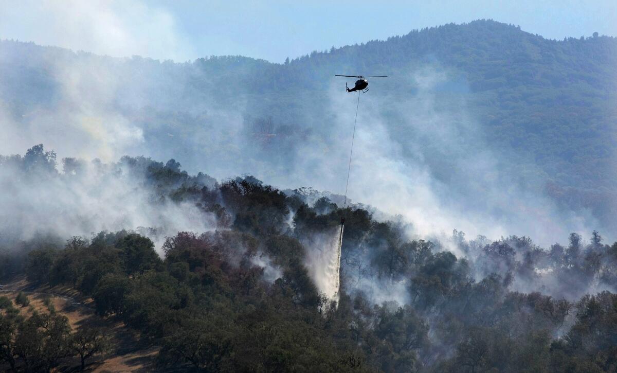 A helicopter makes a water drop on a wildfire hotspot on Sept. 20 in Carmel Valley, Calif.