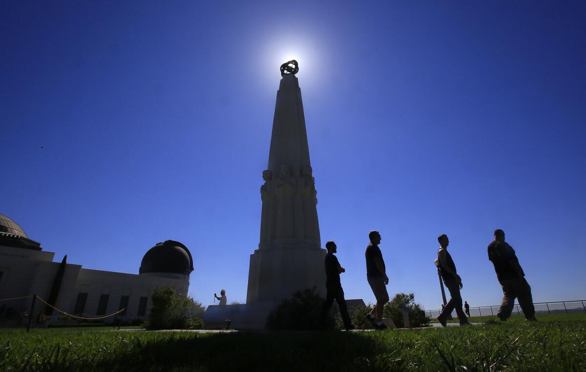 Sept. 22, 2014: Visitors walk past the Astronomers Monument at Griffith Observatory as the sun shines behind it.