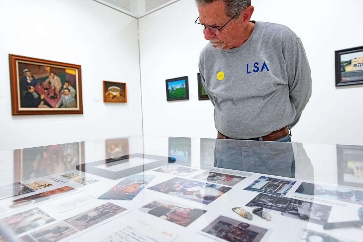 Les Card, of North Tustin, examines photos and mementos of the artist Emigdio Vazquez.