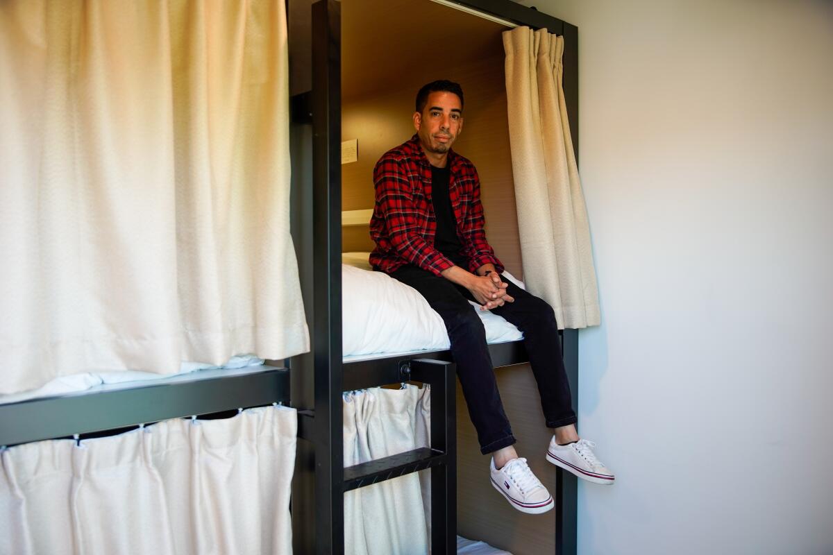 Michael Baez, a resident at the Eddy Co-Living space, sits on a bed in a pod at the space in Hollywood.