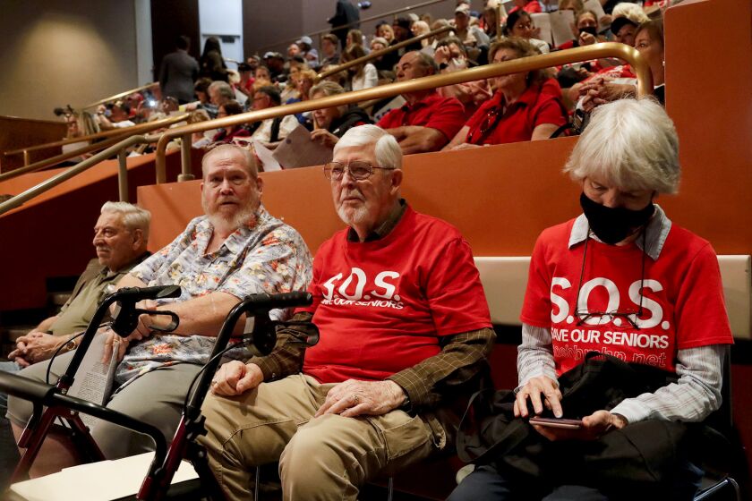 Bob Harold and Suzan Neil, in red shirts and residents of the Scandia mobile home park, attend the packed city council chambers to share their concerns the city is not putting a possible ballot measure for a mobile home rent stabilization ordinance (RSO) during Huntington Beach city council meeting on Tuesday.