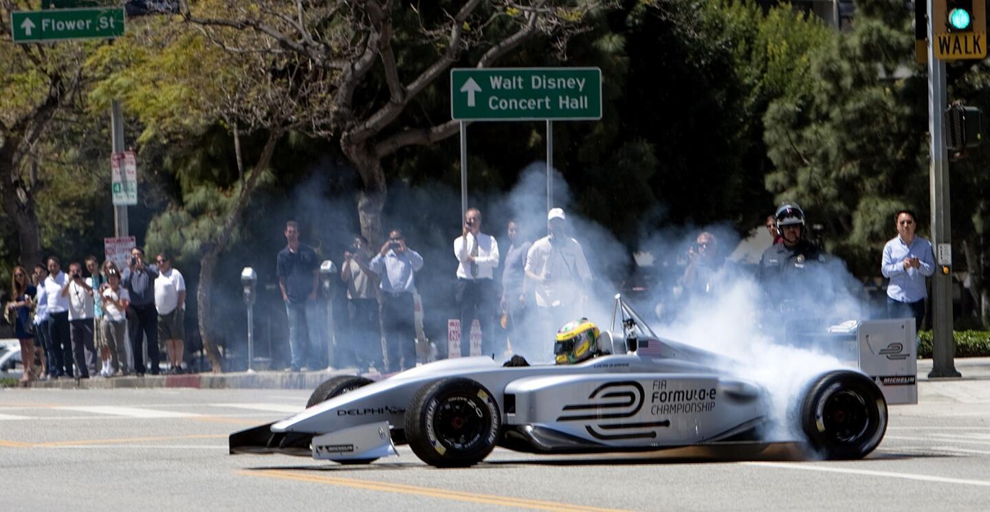 Driver Lucas di Grassi spins his wheels making turns while demonstrating the new Formula E electric race car prototype on Hope Street in downtown L.A.