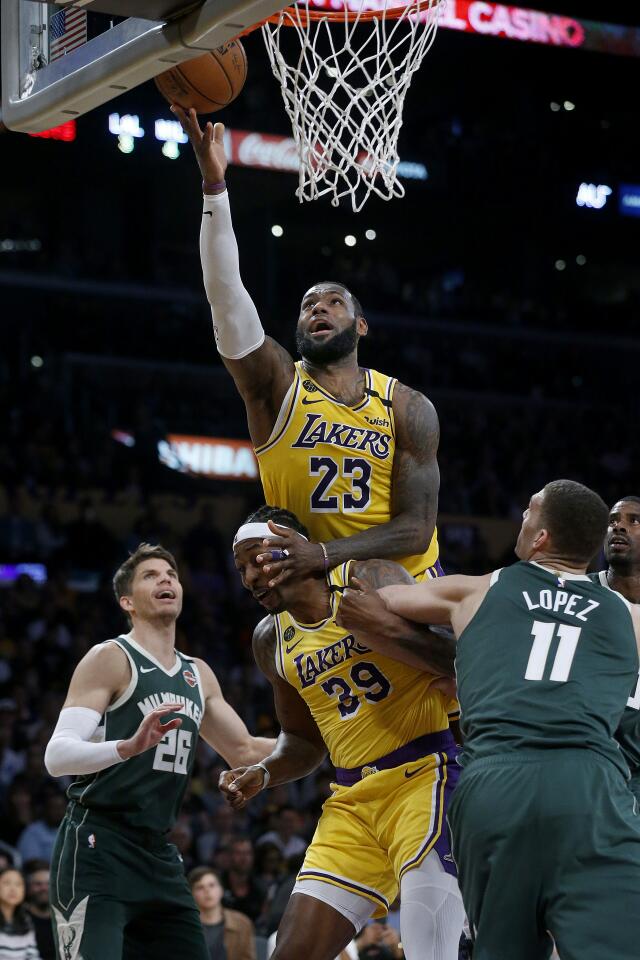 LeBron James scores a basket from Dwight Howard's back during the second half of a game against the Bucks on March 6 at Staples Center.