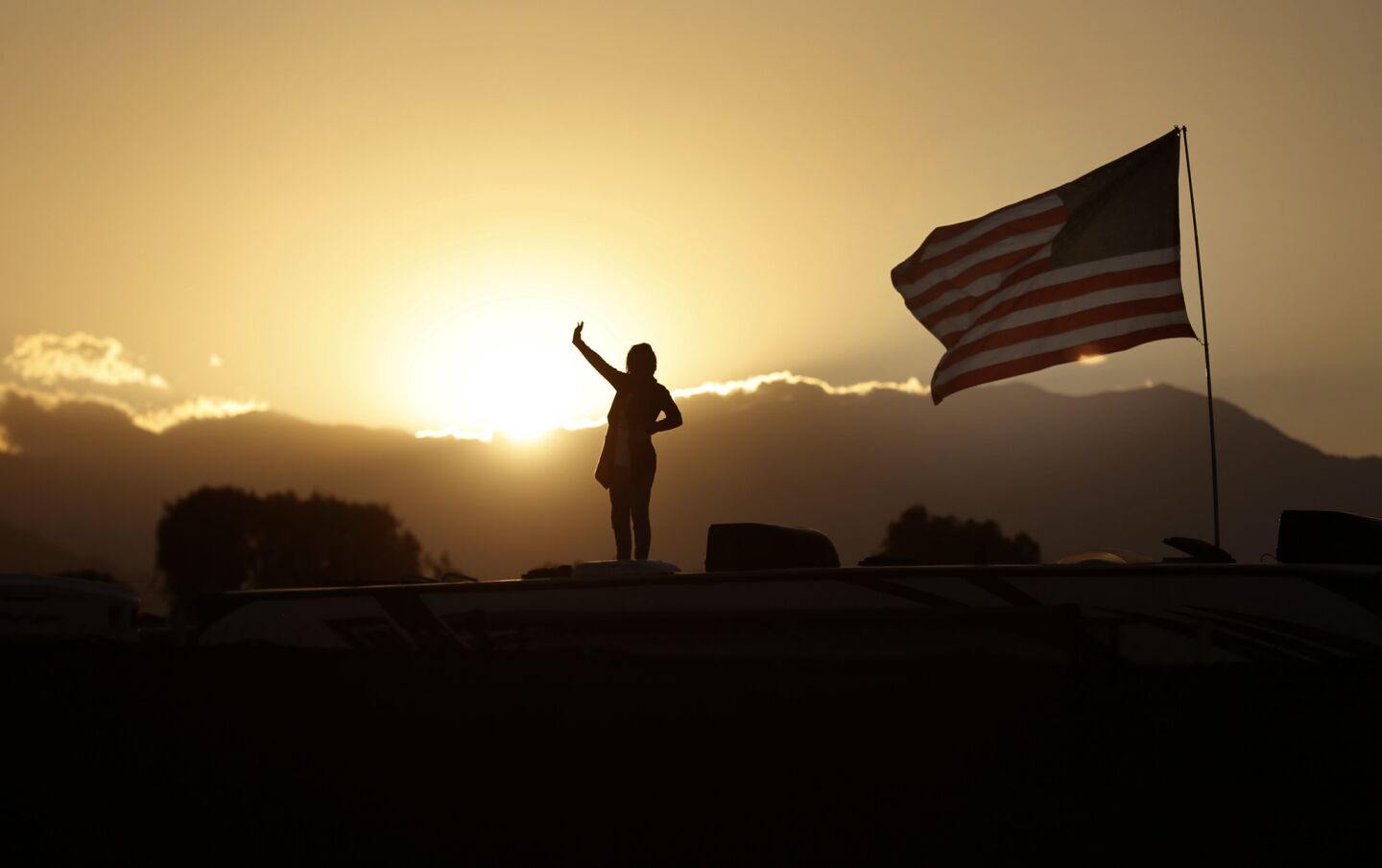 A country music fan waves to friends from the top of an RV at sunset in the RV Resort as she attends the 10th anniversary of Stagecoach Country Music Festival at the Empire Polo Club in Indio on Thursday.
