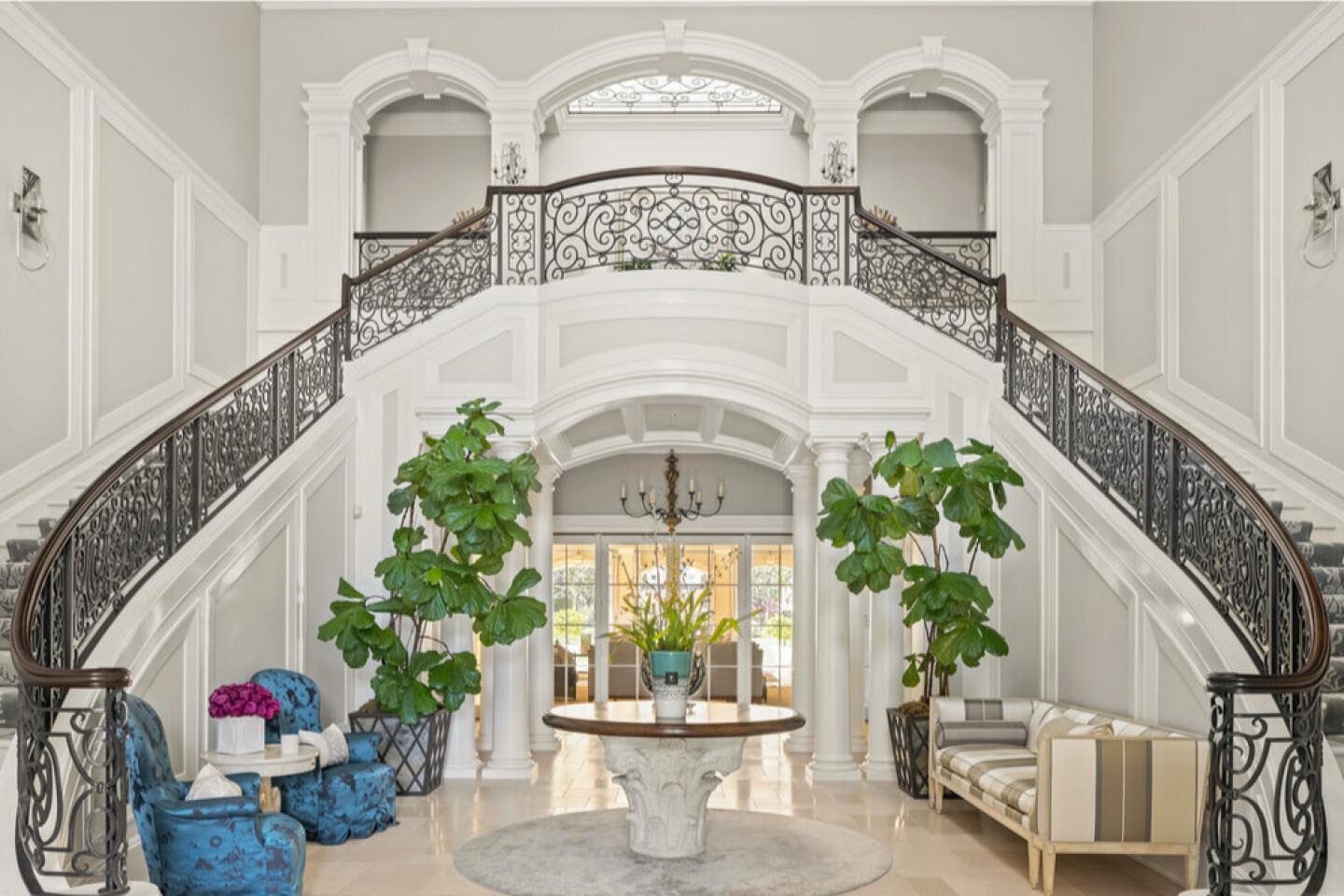 The entry with double stairway with railings, plants and furnishings.