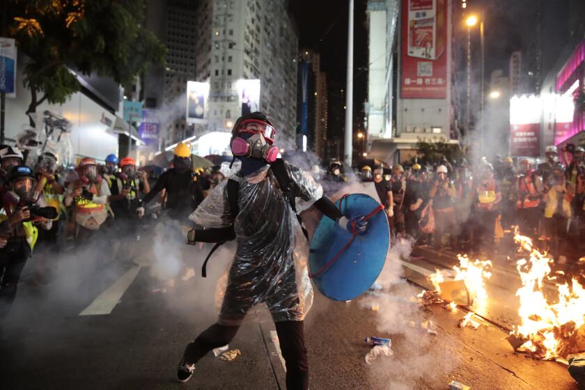 A protestor hurls back an exploded tear gas shell at police officers in Hong Kong, Saturday, Aug. 31, 2019. A large fire blazed across a main street in Hong Kong on Saturday night, as protesters made a wall out of barricades and set it afire. Hundreds of protesters gathered behind the fire, many pointing laser beams that streaked the night sky above them. (AP Photo/Jae C. Hong)