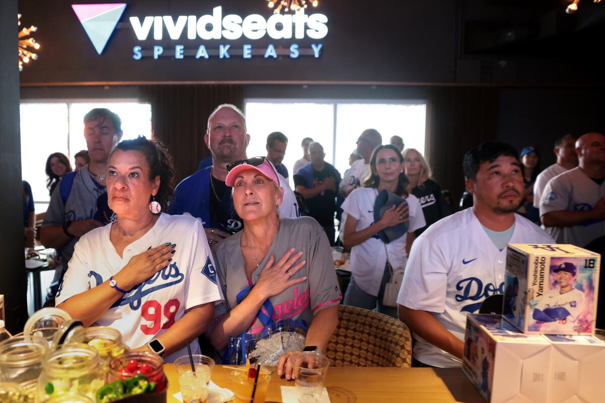 Dodger fans listen to the National Anthem at the speakeasy under the Right Field Pavilion at Dodger Stadium.