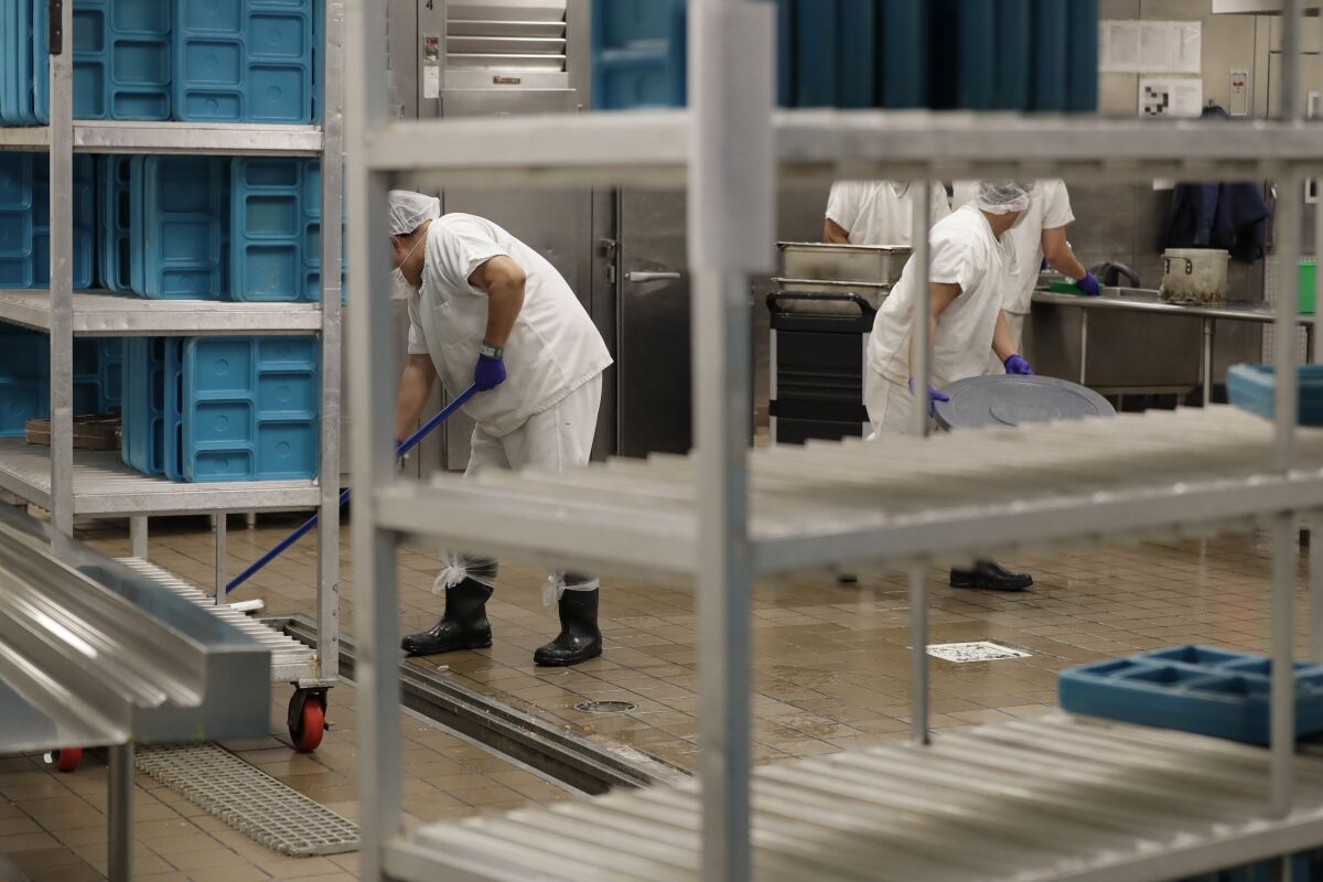 FILE - Workers are shown in the kitchen of The GEO Group's immigration detention center in Tacoma, Wash., during a media tour, Sept. 10, 2019. After a federal jury determined on Oct. 27, 2021, that detainee workers were entitled to minimum wage for cooking, cleaning and other work they perform, the company suspended the work program pending an appeal, rather than increase the detainees' pay. (AP Photo/Ted S. Warren, File)