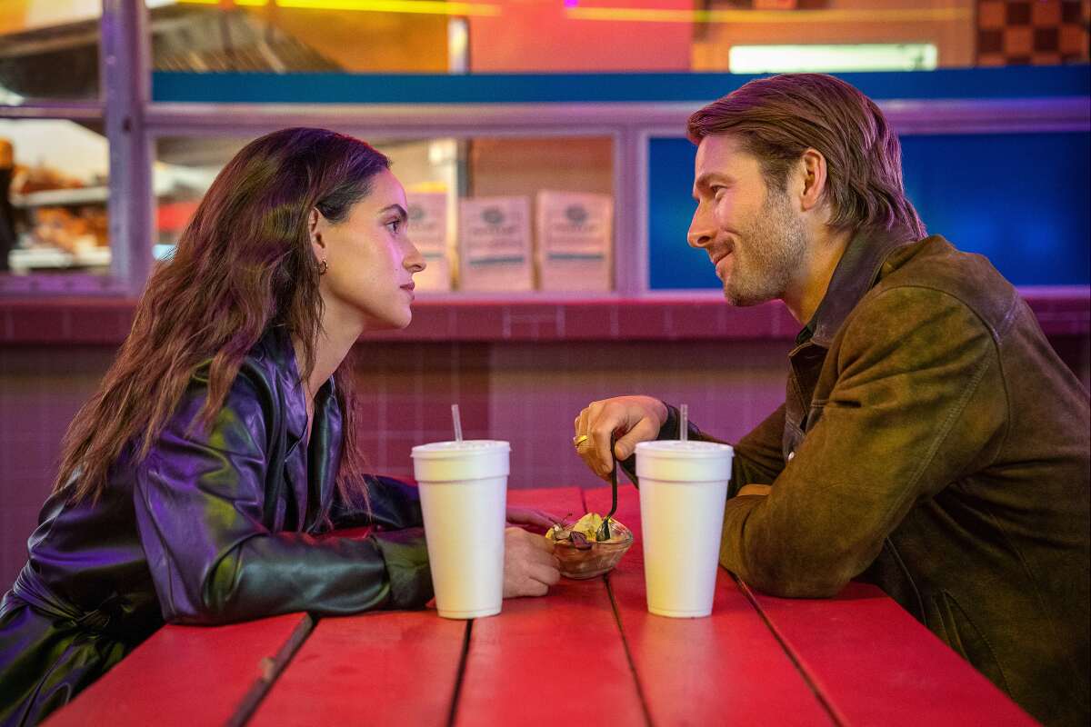 A woman and a man smiling at each other over a picnic table