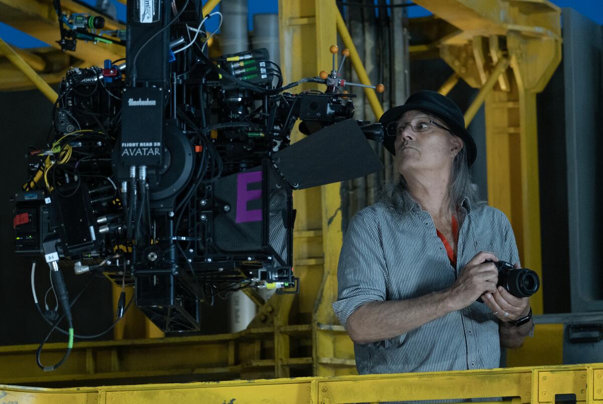 Cinematographer Russell Carpenter on the set of "Avatar: Way of the Water" standing near a specialized film camera. 