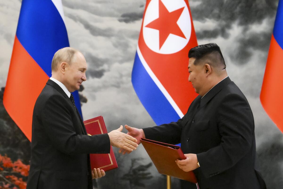 Russian President Vladimir Putin, left, and North Korea's leader Kim Jong Un exchange documents.