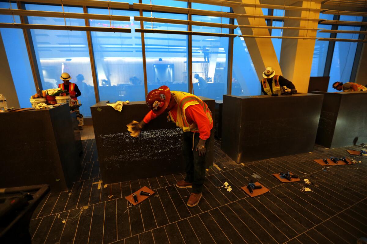Marble finisher Bravlio Fuentes, foreground, works on a hotel check-in pod made of Luccon fiber-optic concrete in the 70th-floor lobby.