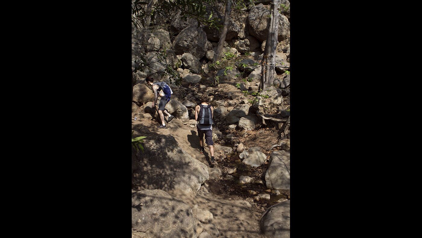 Hikers make their way to the waterfalls behind the ruins.