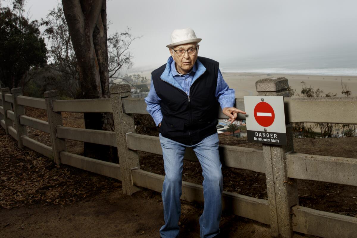 Norman Lear pointing at a 'danger' sign in 2016