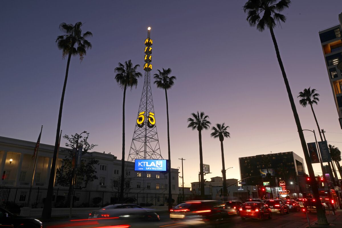 A KTLA broadcast tower at sunset surrounded by palm trees.
