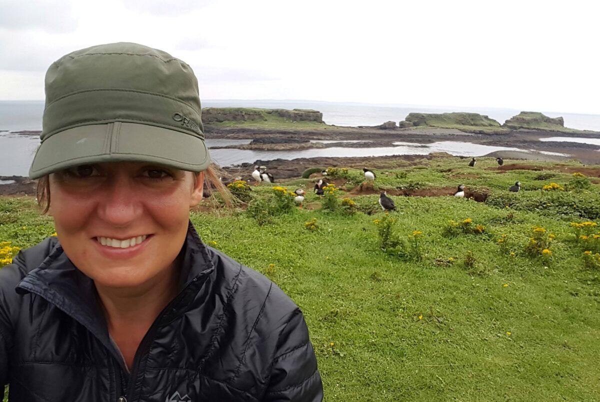 Krisztina Scheeff on a photo tour in Scotland with the photogenic Atlantic puffins behind her.