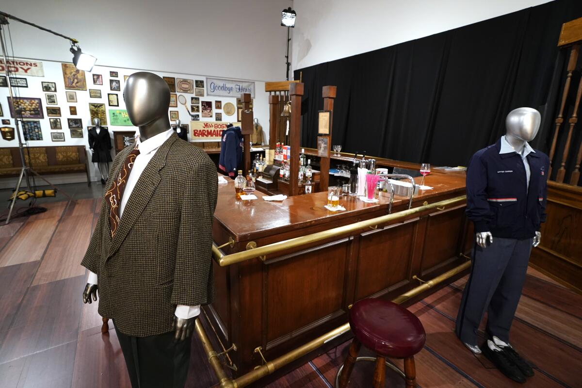 The wooden bar used on the set of 'Cheers' and some costumes, including a tweed brown suit and a blue jacket on mannequins.